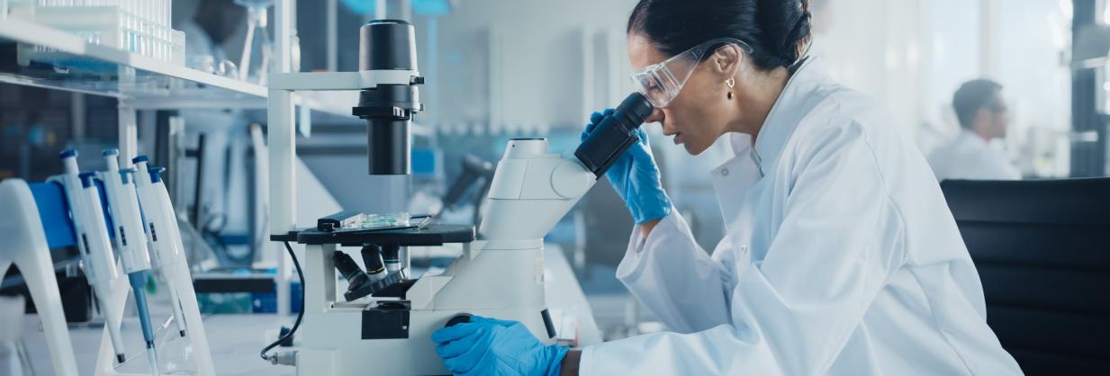 Scientist in a lab, looking through a microscope.