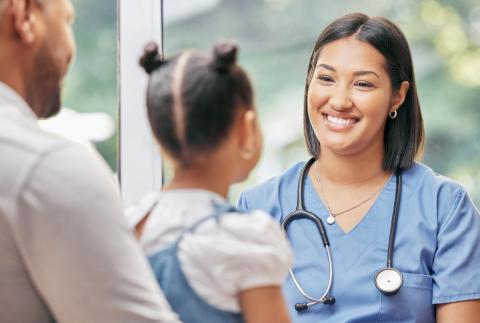 Registered nurse smiling at a young girl and her father.